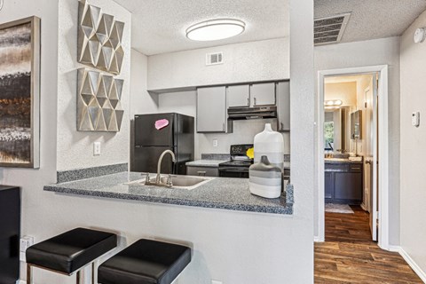 Modern kitchen with stainless steel appliances and a breakfast bar at Laurels of Sendera apartments in Arlington, TX